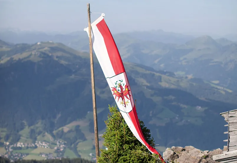 Tiroler Flagge weht vor einer alpinen Berglandschaft.