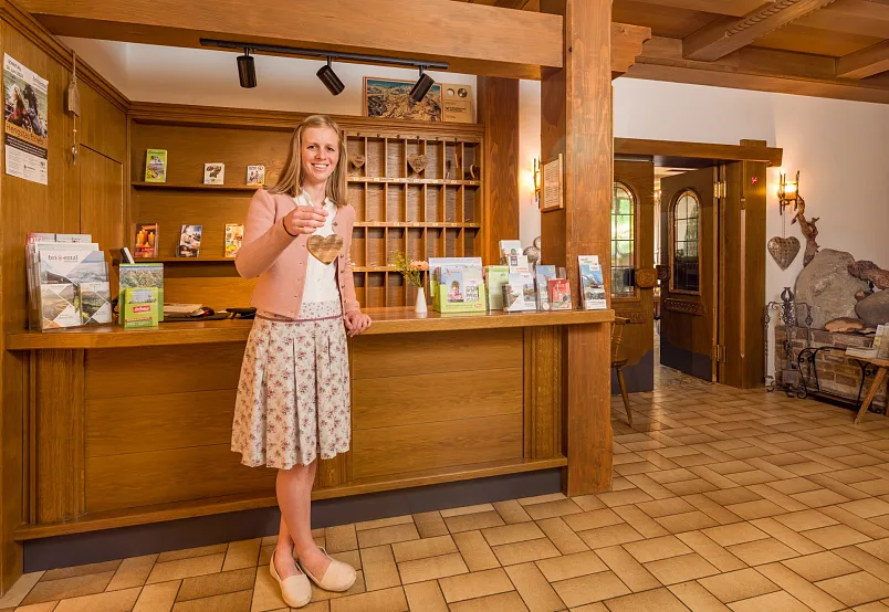 Frau in Empfangsbereich eines traditionellen Hotels mit Broschüren und Holzdekor.