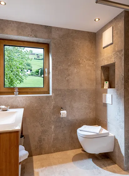 Modernes Badezimmer mit Fenster und Blick auf grüne Landschaft.