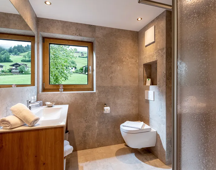 Modernes Badezimmer mit Fenster und Blick auf grüne Landschaft.