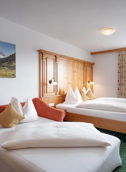 Hotelkamer met twee bedden, houten meubels en een schilderij van de Alpen aan de muur.