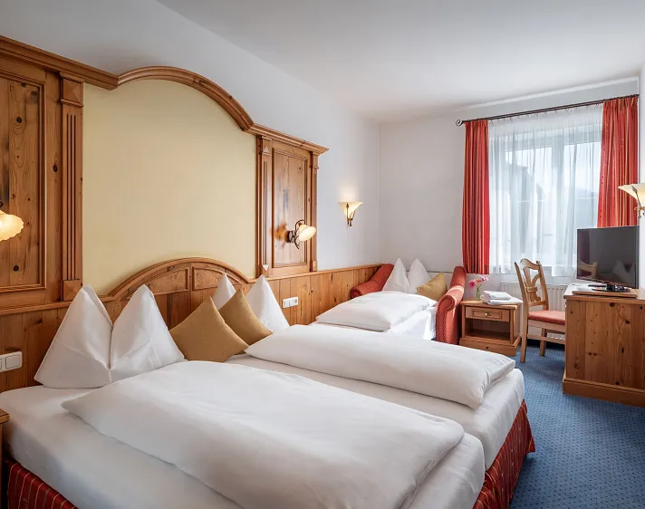 Hotelkamer met twee eenpersoonsbedden, houten meubels en een raam met gordijnen.