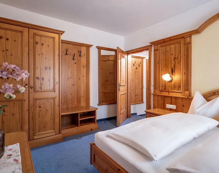 Gemütliches Hotelzimmer aus Holz mit Doppelbett und Kleiderschränken.