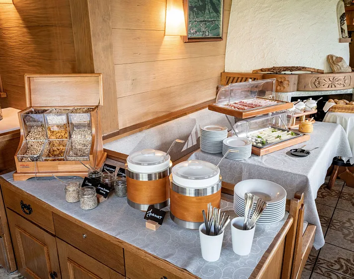 Frühstücksbuffet in einem gemütlichen Alpenhotel mit verschiedenen Speisen und rustikaler Einrichtung.