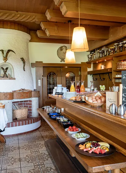 Gemütlicher Frühstücksraum einer alpinen Lodge mit Kamin, Holzmöbeln und Buffet in Tirol.
