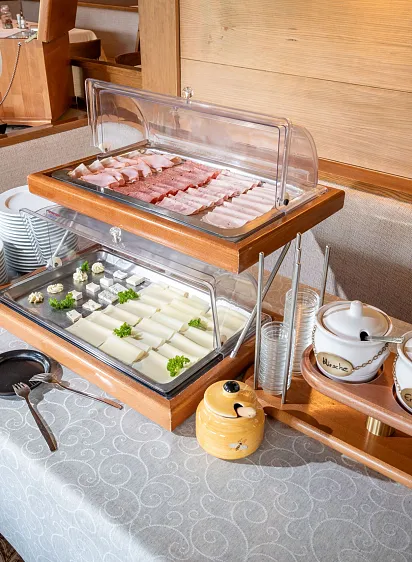 Frühstücksbuffet mit Auswahl an Wurst, Käse und Joghurt in einem Tiroler Restaurant.