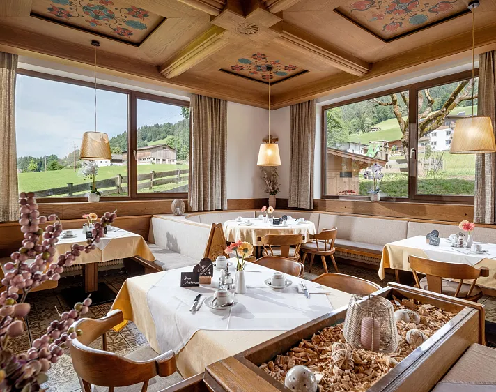 Gemütliches Restaurant in alpiner Umgebung mit Holzmöbeln und großen Fenstern, die die Berglandschaft zeigen.
