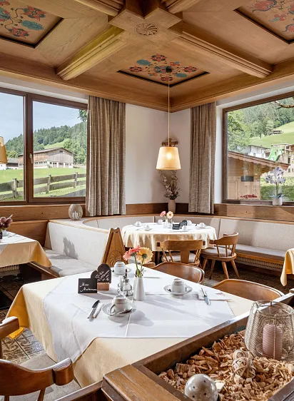 Gemütliches Restaurant in alpiner Umgebung mit Holzmöbeln und großen Fenstern, die die Berglandschaft zeigen.