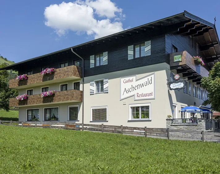 Gasthof Aschenwald mit Blumendekoration in Tirol unter blauem Himmel.