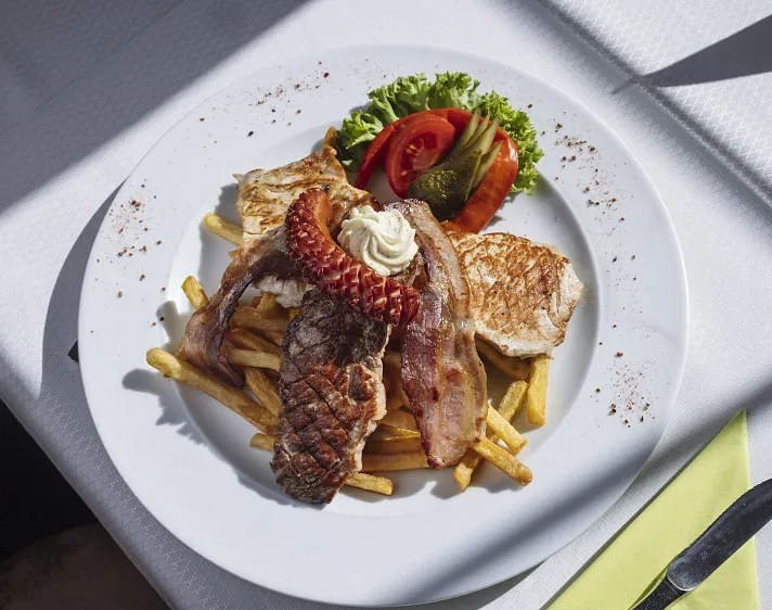 Ein Teller mit gegrilltem Fleisch, Pommes frites und gemischtem Salat.