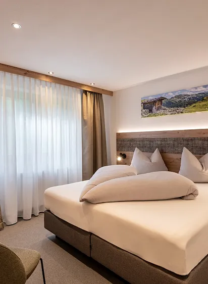Hotelzimmer mit Doppelbett und Bergmotiv an der Wand.