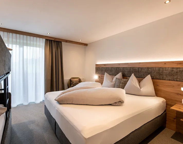 Modern eingerichtetes Hotelzimmer mit Doppelbett und Bettwäsche.