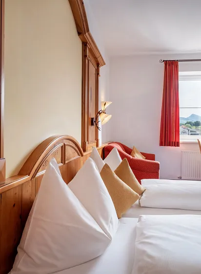Slaapkamer in hotel met houten interieur, twee bedden, uitzicht op bergen en een televisie op een houten kastje.