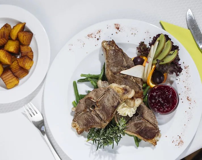 Teller mit Lamm, Gemüse, Preiselbeeren und gebackenen Kartoffeln.