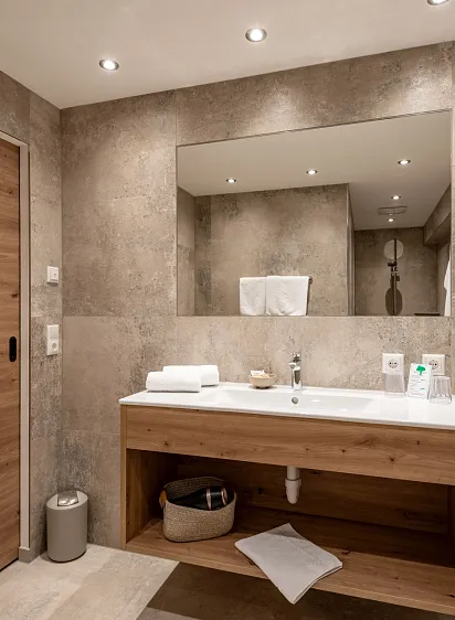 Badezimmer mit Waschbecken, großem Spiegel und Holzakzenten.