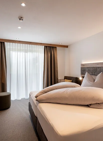 Modern eingerichtetes Hotelzimmer mit Doppelbett und Schreibtisch in einem hellen Raum.