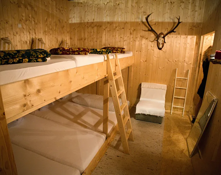 Holzvertäfeltes Schlaflager mit Stockbetten und Jagdtrophäe an der Wand.