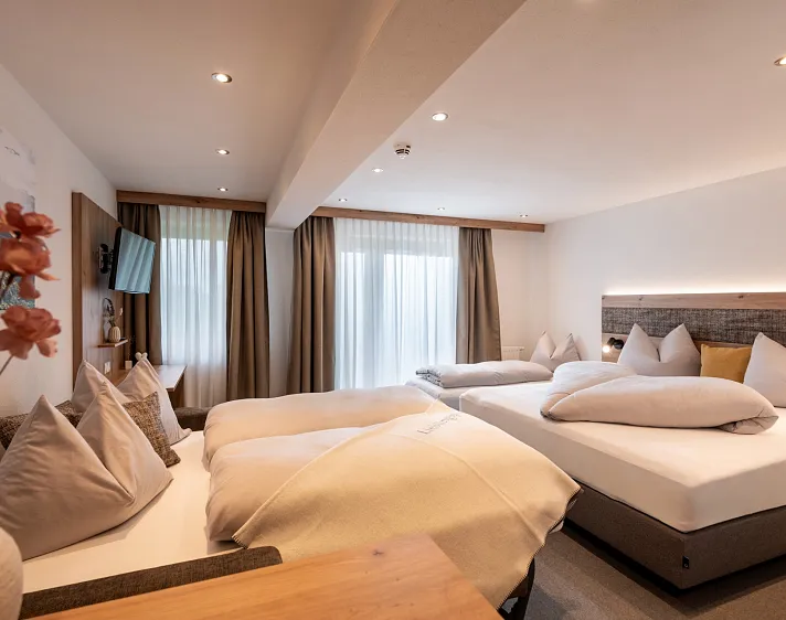 Modernes Hotelzimmer mit zwei Doppelbetten und heller Beleuchtung.
