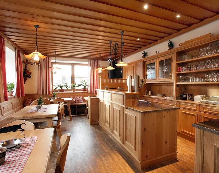 Holzvertäfeltes Gasthausinterieur mit Tischen, Bänken und Barbereich.