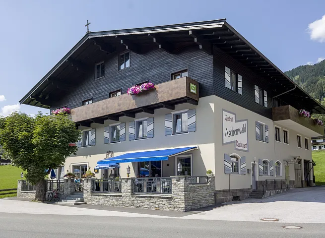 Ein traditionelles Gasthaus mit Holzbalkon und Garten in den Tiroler Alpen.