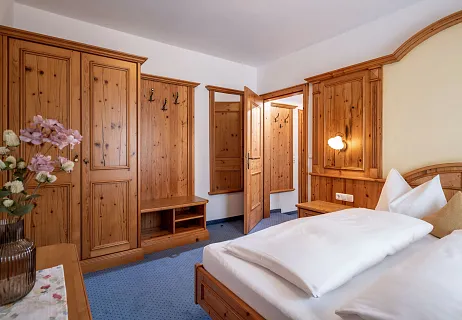 Houten slaapkamer in een hotel met een bed, kledingkast en bloemen op een tafel.