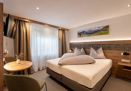 Hotelzimmer mit Doppelbett und Bergmotiv an der Wand.