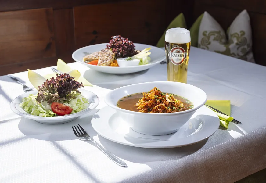 Ein Wiener Schnitzel mit Kartoffeln, Preiselbeersauce und Salat auf einem weißen Teller.