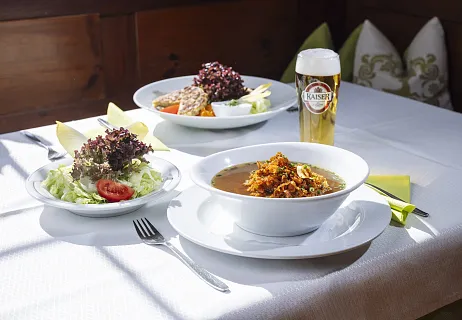 Ein Wiener Schnitzel mit Kartoffeln, Preiselbeersauce und Salat auf einem weißen Teller.
